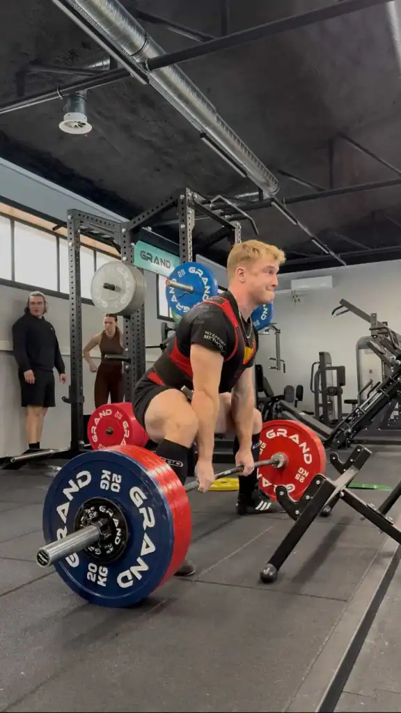 Mężczyzna kucający przy sztandze chwilę przed poderwaniem