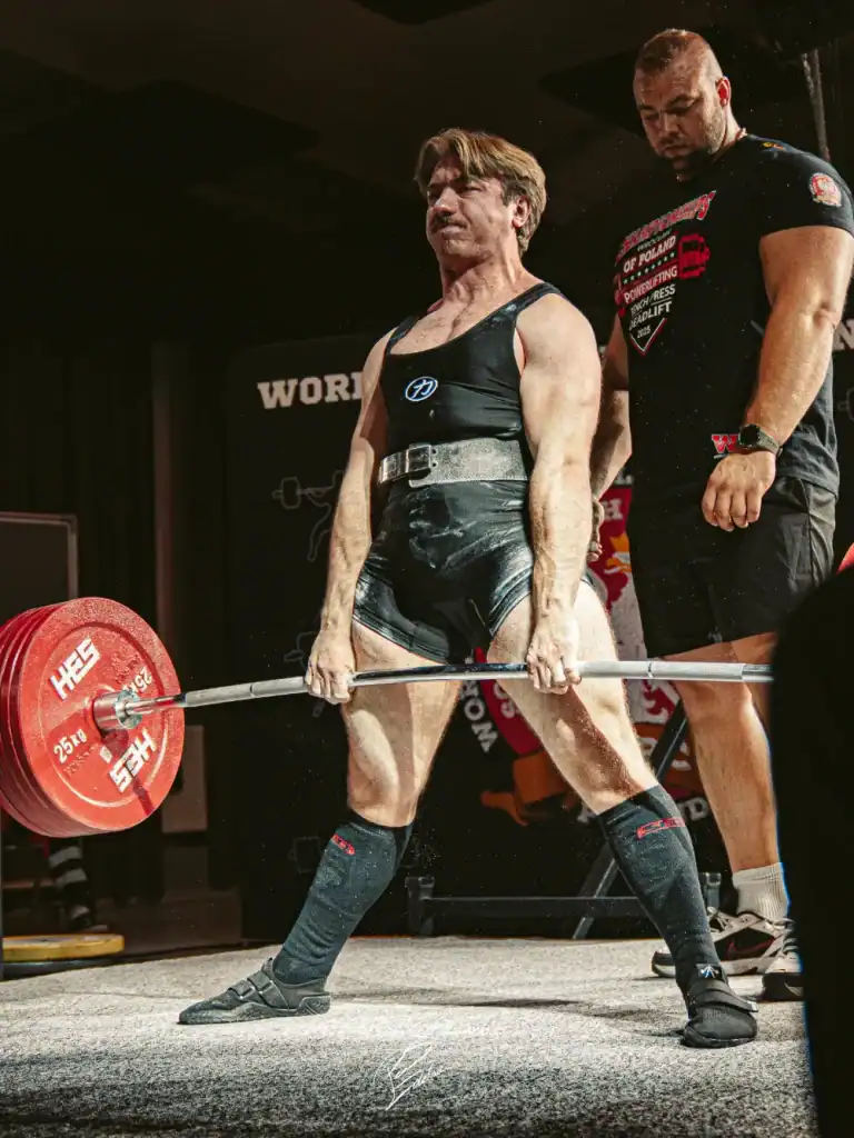 Mężczyzna w sportowym stroju dźwigający sztangę w martwym ciągu