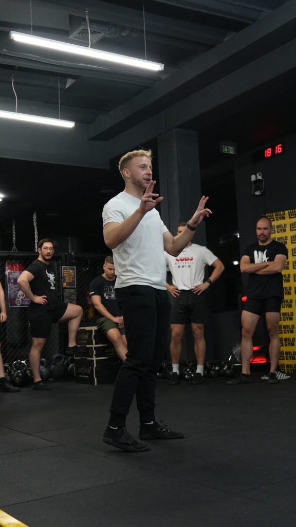 mężczyzna na sali sportowej prowadzi wykład dla innych zawodników