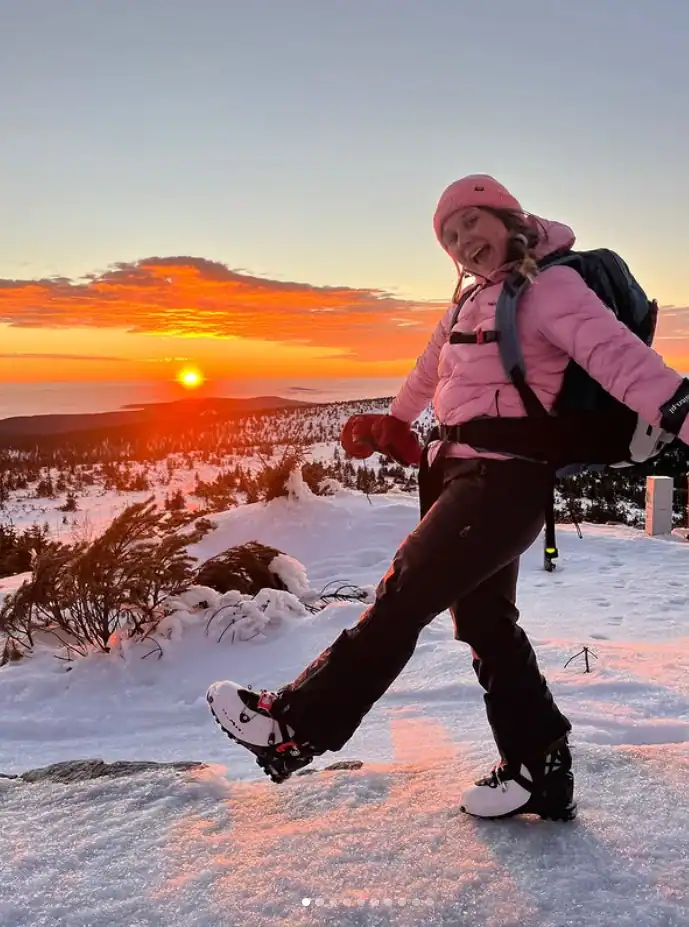 Kobieta na snowboardzie na śniegu podczas zachodu słońca w górach.