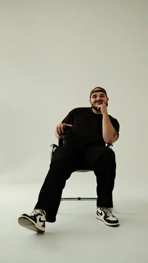 Mężczyzna w sportowym stroju siedzi na krześle, uśmiecha się do kamery.